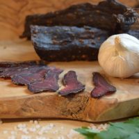 biltong on cutting board with side of garlic